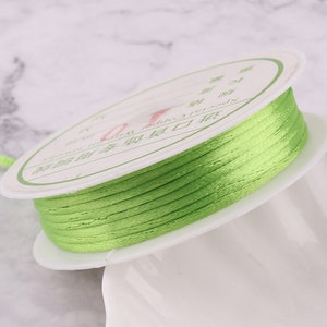 May include: A spool of bright green thread wound around a white label with Chinese text. The label reads "Chinese Silk Thread".