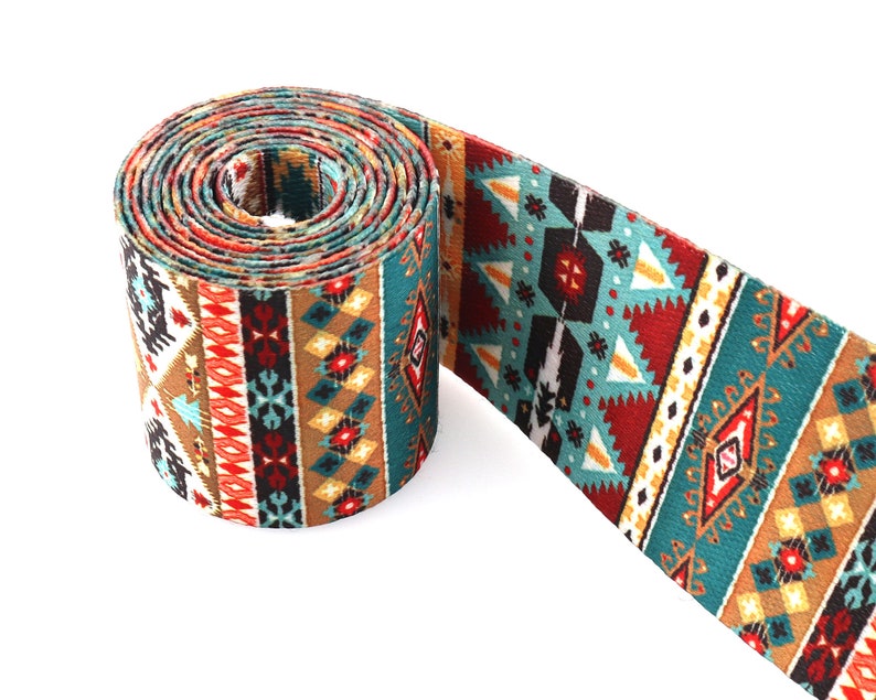 Op de afbeelding: Een opgerolde turquoise, bruine, rode en witte geweven band met geometrische patronen.