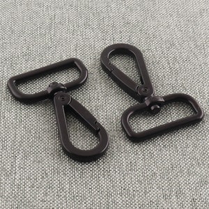 May include: Two black metal swivel clasps with a rectangular loop on one end and a hook on the other end.