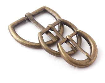 May include: Three antique gold-toned metal belt buckles. The buckles are all the same size and shape, but they are arranged in a staggered pattern. The buckles are designed to be used with a belt strap.