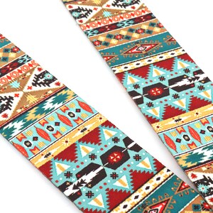 Op de afbeelding: Een gitaarband met een kleurrijk geometrisch patroon in tinten rood, blauw, geel en bruin. Het patroon doet denken aan Native American art.