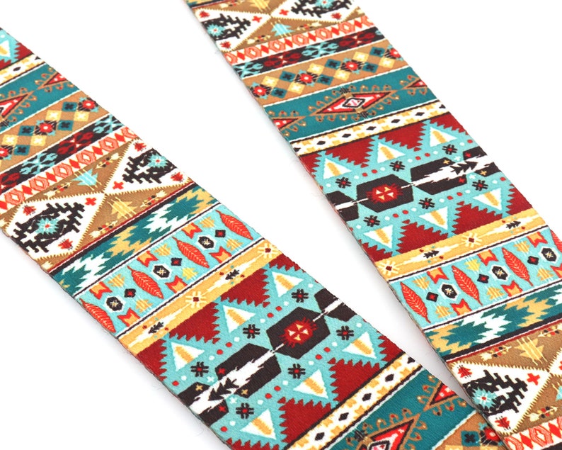 Op de afbeelding: Een gitaarband met een kleurrijk geometrisch patroon in tinten rood, blauw, geel en bruin. Het patroon doet denken aan Native American art.