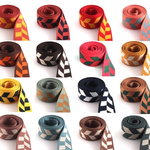 May include: Assortment of 12 colorful woven ribbon trims with geometric patterns. The ribbons are in various colors, including red, blue, green, yellow, brown, and black. Each ribbon has a diamond pattern.