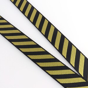 May include: Black and gold striped webbing with a chevron pattern.