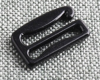 May include: Black plastic bra strap slider. The slider has two loops and a hook.