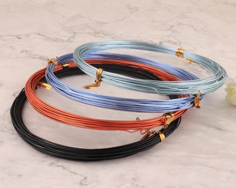 Puede incluir: Cuatro carretes de alambre en diferentes colores: negro, cobre, azul claro y un tono de azul más claro. El alambre está enrollado alrededor de cada carrete.