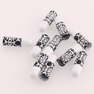 May include: A group of ten white and black geometric patterned caps. The caps are cylindrical and have a black and white geometric pattern.