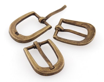 May include: Three antique gold-toned metal belt buckles. The buckles are different sizes and styles.