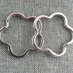 May include: Two silver metal keyrings shaped like a flower with five petals. The keyrings are linked together.