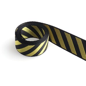 May include: Black and yellow striped ribbon with a diagonal pattern. The ribbon is rolled up and the end is hanging down.