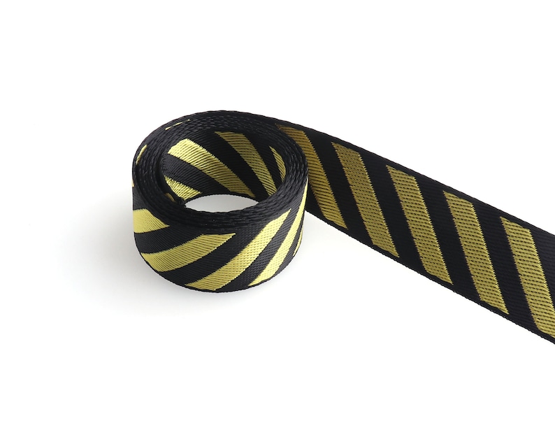 May include: Black and yellow striped ribbon with a diagonal pattern. The ribbon is rolled up and the end is hanging down.