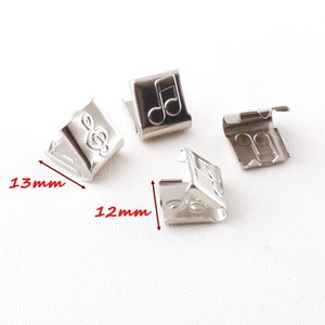 Puede incluir: Cuatro tiradores de cremallera de metal plateado con un diseño de nota musical. Cada tirador mide 12 mm por 13 mm.