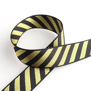 May include: Black and yellow striped ribbon with a diagonal pattern. The ribbon is folded in a loop.