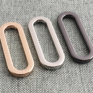 May include: Three oval-shaped metal rings in gold, silver, and black.