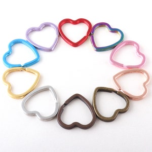 Pode incluir: Conjunto de chaveiros em forma de coração em várias cores, incluindo vermelho, azul, roxo, rosa, dourado, prateado e bronze.