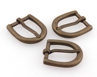 May include: Three antique gold-toned metal belt buckle slides. The buckles are D-shaped with a smooth finish.