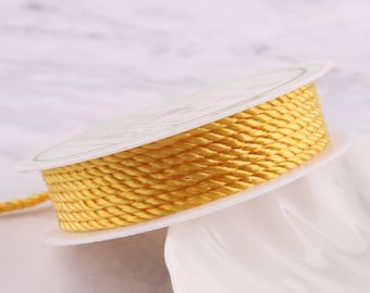 Puede incluir: Una bobina de cordón trenzado amarillo. El cordón está enrollado alrededor de una bobina de plástico blanca.