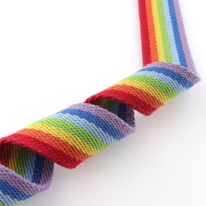 May include: A rainbow striped woven webbing with a purple, blue, green, yellow, orange, and red color scheme.