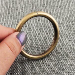 May include: A gold-toned metal ring with a smooth, rounded surface. The ring is approximately 2 inches in diameter.