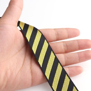 May include: Black and gold striped ribbon with a textured surface.