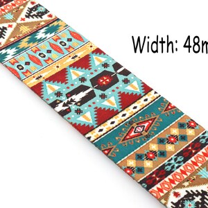 Op de afbeelding: Een kleurrijke gitaarband met een geometrisch patroon in tinten rood, blauw, geel en bruin. De band is 48 mm breed.