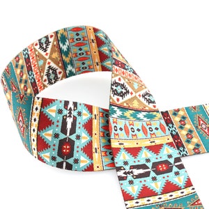 Op de afbeelding: Een geweven gitaarband met een kleurrijk geometrisch patroon in tinten van teal, rood, bruin en goud.