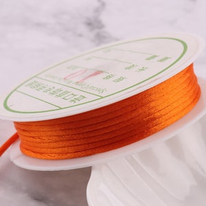 May include: A spool of orange waxed cord with a white label that reads "Special Cord for Jewelry Making".