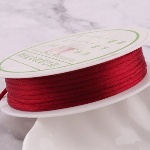 May include: A spool of red satin cord, wound around a white plastic spool with a label in Chinese characters.