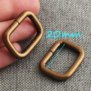 May include: Two gold-toned metal D-rings, each measuring 20 mm in length. The rings are open and have a smooth, polished finish.