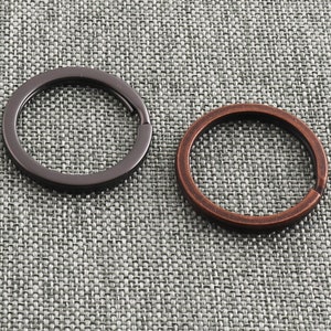 Peut inclure: Deux porte-clés, un noir et un cuivre, sur un fond texturé gris.