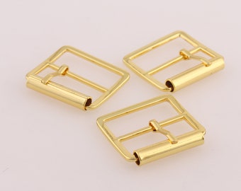 May include: Three gold-toned metal belt buckles. Each buckle has a rectangular shape with a smooth, polished finish.