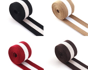 Könnte beinhalten: Vier Rollen gestreiftes Gurtband in Schwarz, Braun, Beige und Rot mit weißen Streifen. Das Gurtband ist aufgerollt und die Enden liegen flach.