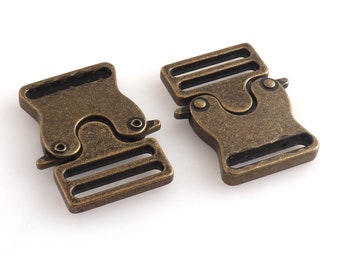 May include: Two antique gold-toned metal side release buckles. Each buckle has two slots for webbing or straps.