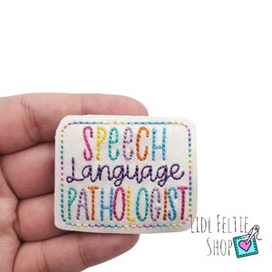 May include: A white felt patch with colorful embroidered text that reads "Speech Language Pathologist".