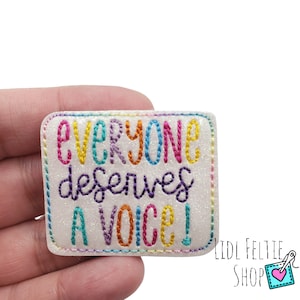 May include: A rectangular, glittery white patch with the embroidered text "EVERYONE deserves A VOICE!" in rainbow colors. The patch has a colorful stitched border. The Lidl Feltie Shop logo is in the bottom right corner.