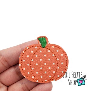 May include: Orange felt pumpkin with white polka dots and a green stem.