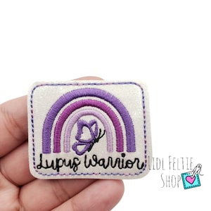 May include: Purple and white glitter iron-on patch with a rainbow and butterfly design. The text "Lupus Warrior" is embroidered on the patch.
