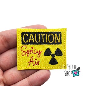 May include: Yellow caution sign with black text that reads "CAUTION" and "Spicy Air". A black radiation symbol is below the text.