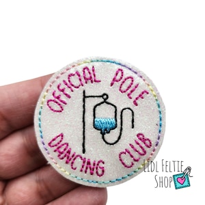 May include: White, round, glittery patch with pink stitching. The patch says "Official Pole Dancing Club" with a black and white illustration of an IV bag hanging from a pole.