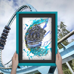 May include: A framed watercolor painting of a blue roller coaster train going upside down with blue, purple, and yellow paint splatters on the white background.