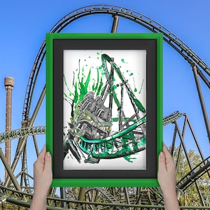 May include: A framed green and black watercolor illustration of a roller coaster going up a hill. The roller coaster is painted in a splatter style with green and black paint.