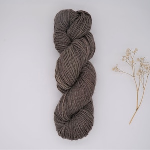 May include: A skein of dark brown yarn, with a subtle color variation, is displayed on a white background.