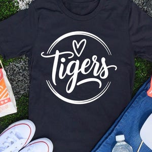 May include: Black t-shirt with a white circle graphic that says "Tigers" with a heart above the word.