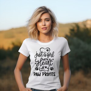 May include: White t-shirt with a black graphic that says "just a girl with a heart full of paw prints".