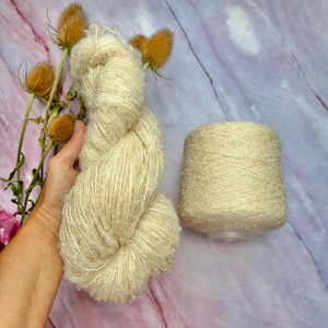 以下が含まれることがあります： クリーム色の糸が2つ、1つはボール状、もう1つは緩い束になっています。糸は柔らかくふわふわしていて、上品な光沢があります。