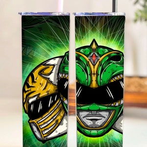 Può includere: Un bicchiere verde e bianco con una grafica di un casco di Power Ranger. Il design include uno sfondo verde con un'esplosione di luce e una cannuccia. Il bicchiere è progettato per mantenere le bevande fredde o calde.