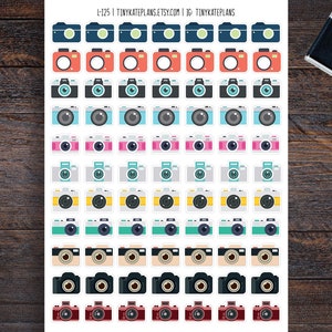 May include: A sheet of 125 colorful camera stickers. The stickers are arranged in 10 rows of 13 stickers each. Each sticker features a different color camera with a white outline.