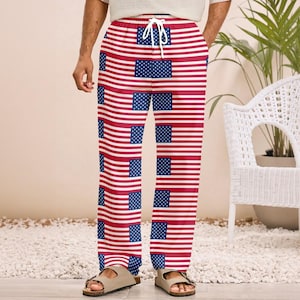 May include: Full-length lounge pants featuring a repeating pattern of the American flag with horizontal red and white stripes and blue rectangles with white stars. The pants have a white drawstring at the elasticized waistband and a loose fit.