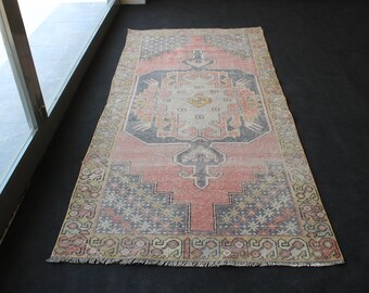 Puede incluir: Una alfombra de estilo vintage con un esquema de color rosa, crema y gris descolorido. La alfombra presenta un medallón central con intrincados patrones florales y geométricos. La alfombra tiene un borde con flecos.