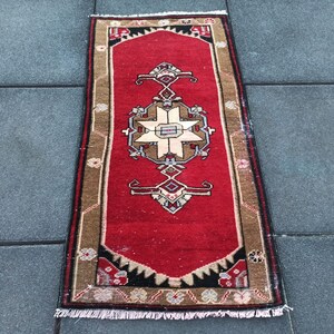 May include: A red runner rug with a traditional floral pattern in shades of brown, cream, and black. The rug has a fringe border and is approximately 60 cm by 120 cm.